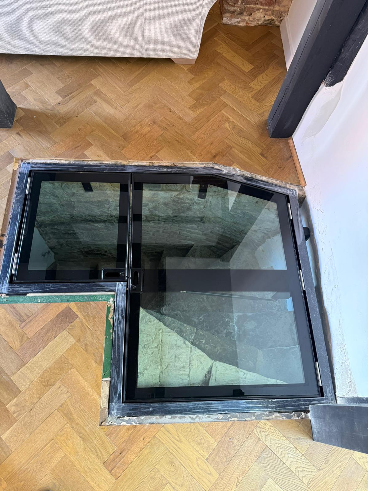 Bespoke L-shaped hinged glass floor doors closed position, herringbone parquet flooring, Burwash East Sussex